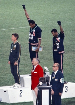 17. kép. Az 1968-as mexikóvárosi olimpia 200 m-es síkfutás számának helyezettei: a fekete sportolók felemelt kézzel, az ausztrál sportoló pedig egy rasszizmus elleni szervezet jelvényével tiltakozik a feketék elnyomása ellen. Forrás: hatharom.com