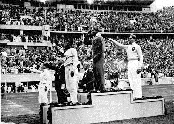 21. kép. Jesse Owens a dobogó tetején, miután megnyerte a távolugrást az 1936-os berlini olimpián. Forrás: wikipedia.org